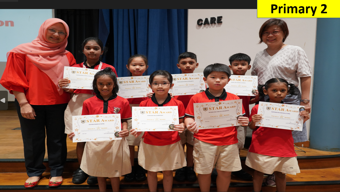 Two teachers and eight Primary 2 students in red uniforms holding Star Award certificates on a stage.